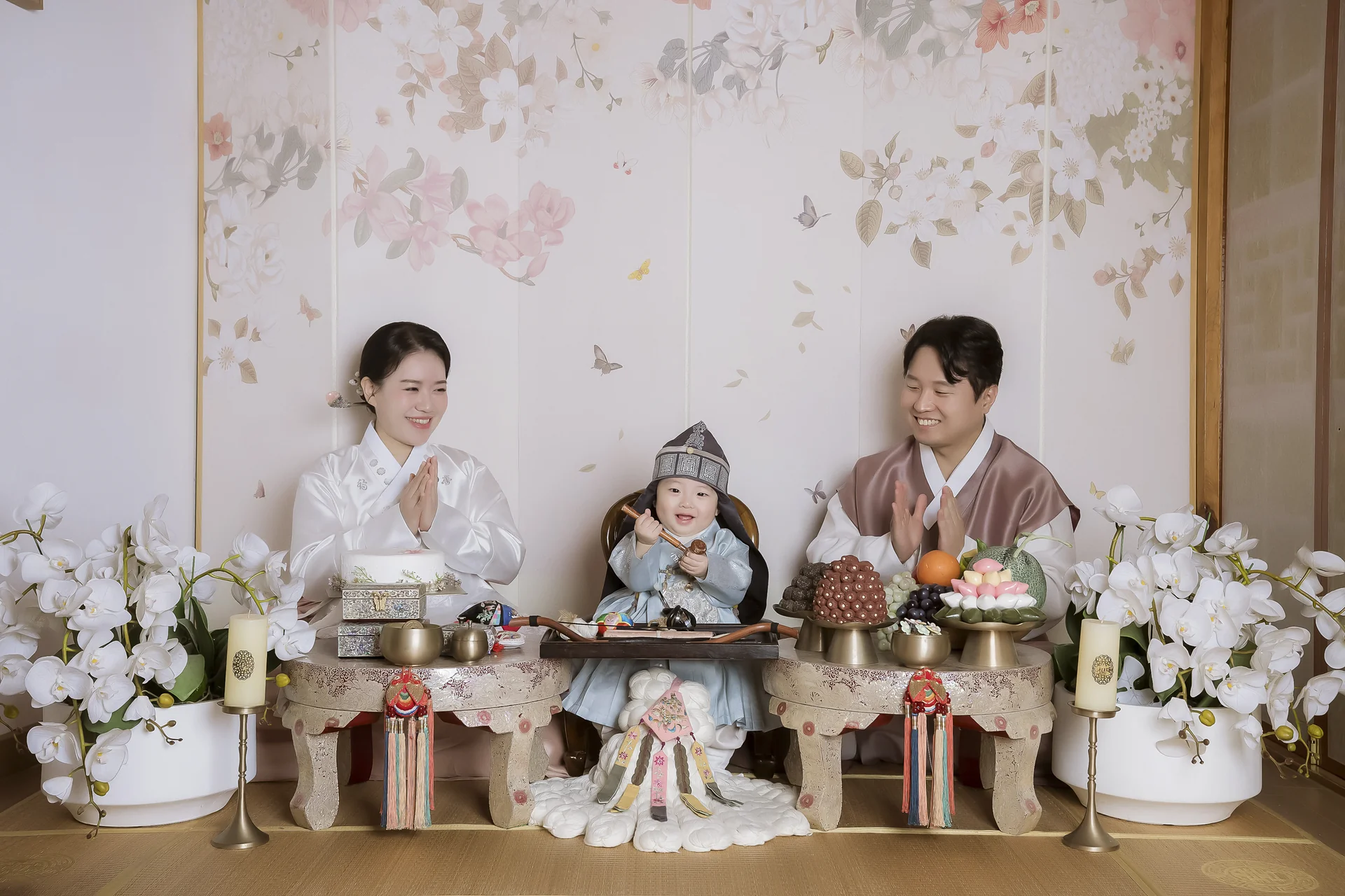 한옥 실내 전통 돌상 앞에서 돌잡이 하는 돌복 아기와 부모님 가족사진